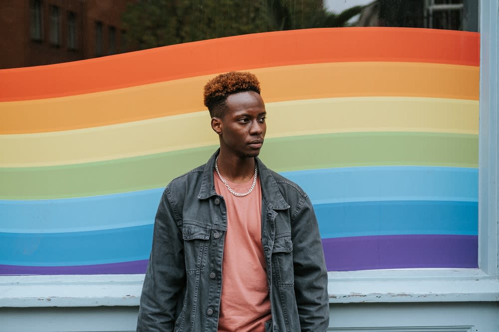 man standing in front of pride flag mural art