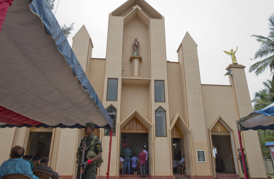 A soldier stands guard during a Catholic Mass outside St. Joseph's church in Thannamunai, Sri Lanka, Tuesday, April 30, 2019. This small village in eastern Sri Lanka has held likely the first Mass since Catholic leaders closed all their churches for fear of more attacks after the Easter suicide bombings that killed over 250 people. (AP Photo/Gemunu Amarasinghe)