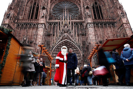 A man dressed as Father Christmas poses with a tourist outside the Cathedral in Strasbourg, France, December 14, 2018. REUTERS/Christian Hartmann