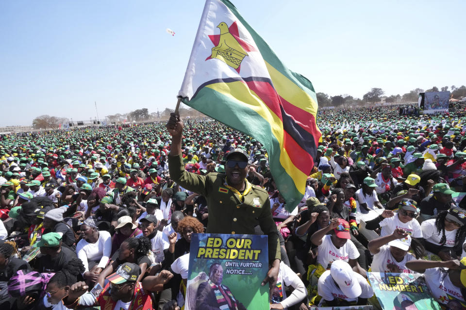 A supporter of Zimbabwean President Emmerson Mnangagwa holds the Zimbabwean flag at a campaign rally in Harare, Wednesday, Aug. 9, 2023. Mnangagwa addressed thousands of supporters in a speech laden with calls for peace, days after his supporters were accused of stoning an opposition activist to death ahead of general elections set for Aug. 23. (AP Photo/Tsvangirayi Mukwazhi)