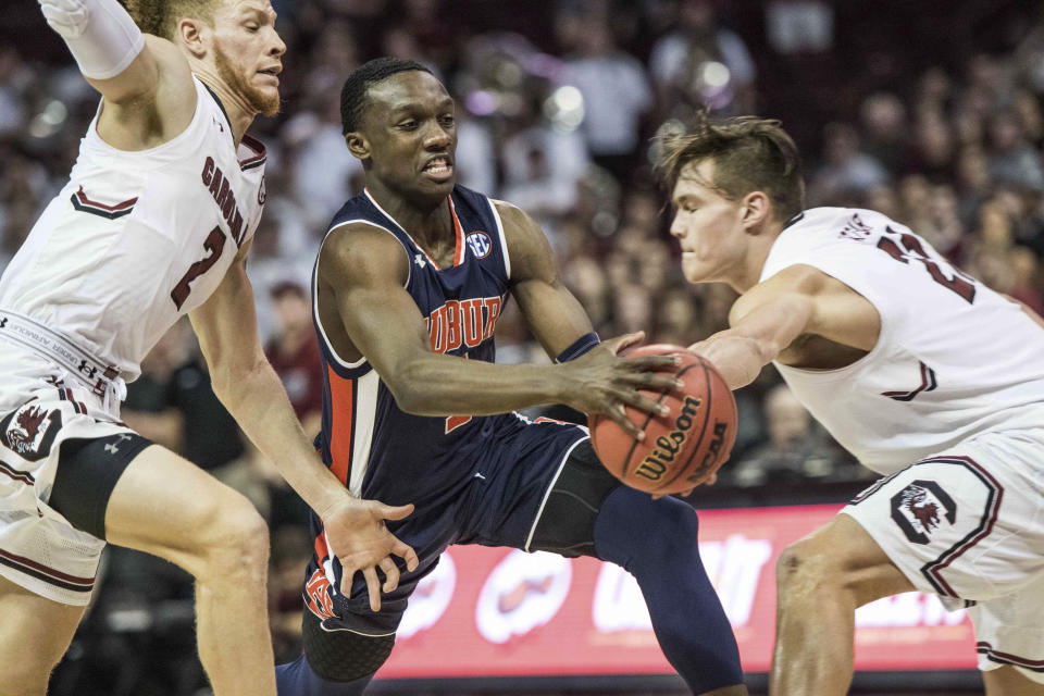 Auburn guard Jared Harper, center, dribbles the ball against South Carolina guard Hassani Gravett (2) and Maik Kotsar, right, during the first half of an NCAA college basketball game Saturday, Feb. 17, 2018, in Columbia, S.C. (AP Photo/Sean Rayford)