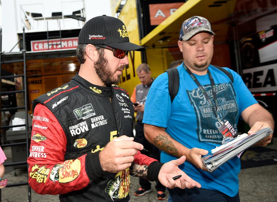 Martin Truex Jr. signs for fans before practice for the NASCAR Cup series auto race, Saturday, Oct. 6, 2018, at Dover International Speedway in Dover, Del.