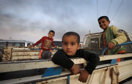 FILE PHOTO: Boys stand at a back of a truck as they flee Ras al Ain town