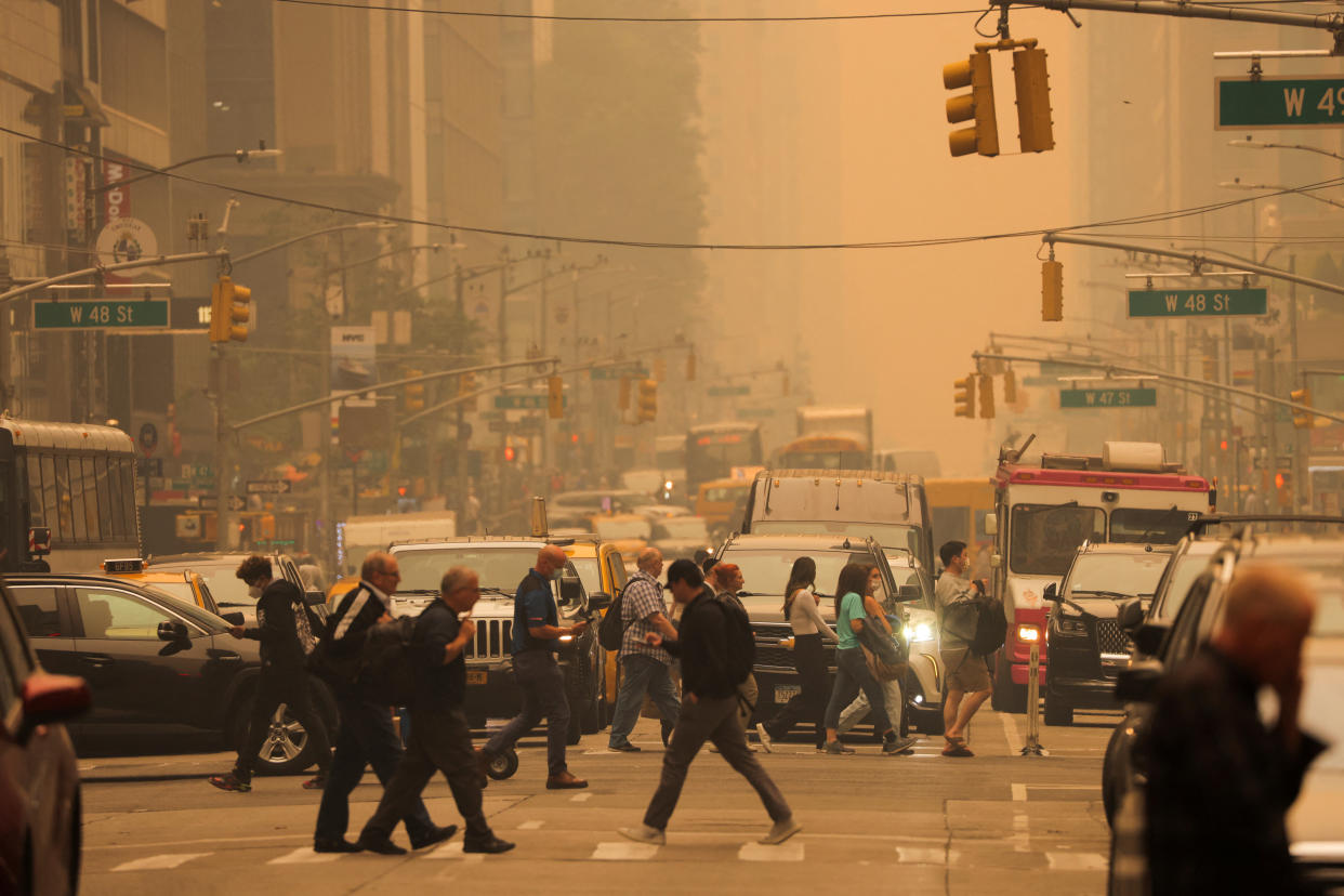 People walk across 6th Avenue in Manhattan on Wednesday as haze and smoke caused by wildfires in Canada blanket New York City. (Andrew Kelly/Reuters)