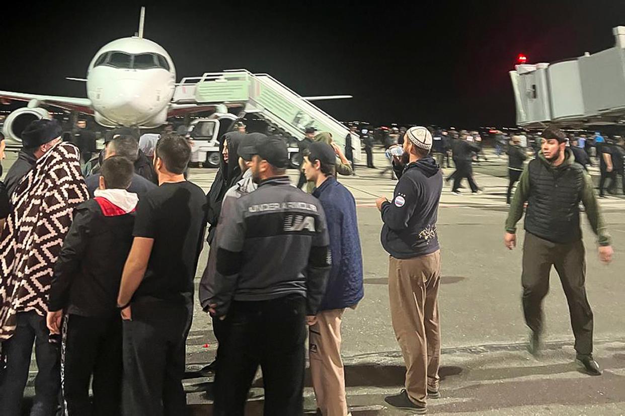 People in the crowd walk shouting antisemitic slogans at an airfield of the airport in Makhachkala, Russia on Monday (AP)