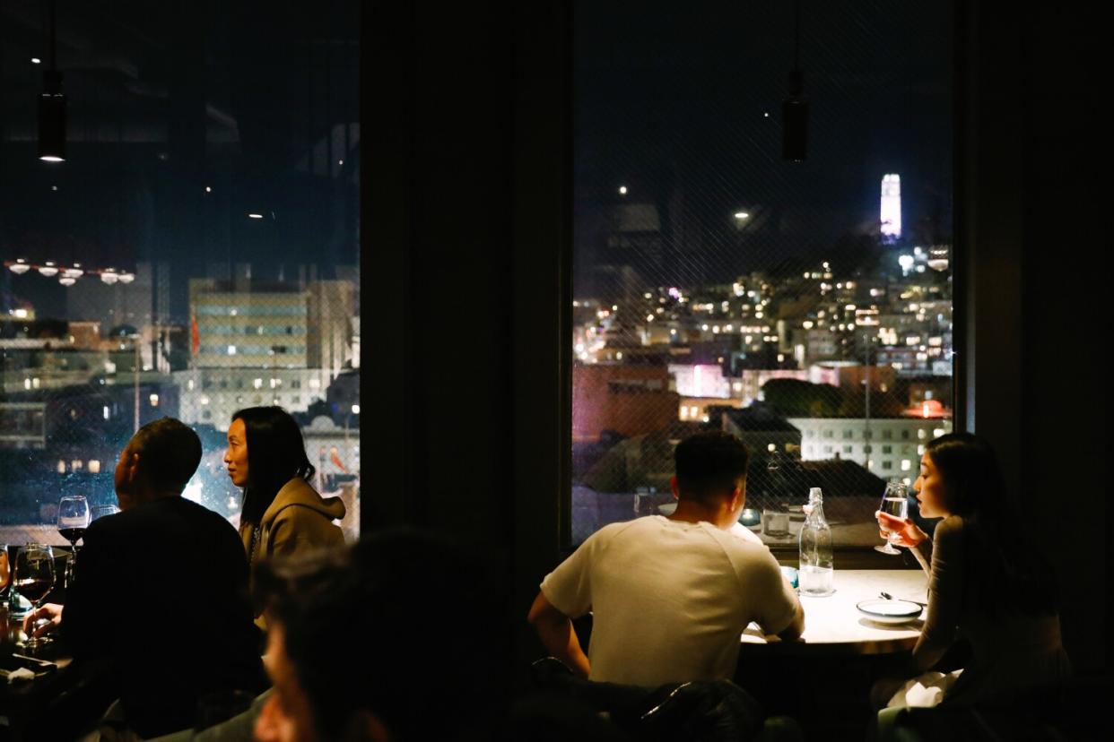 Diners sit along windows revealing a cityscape.