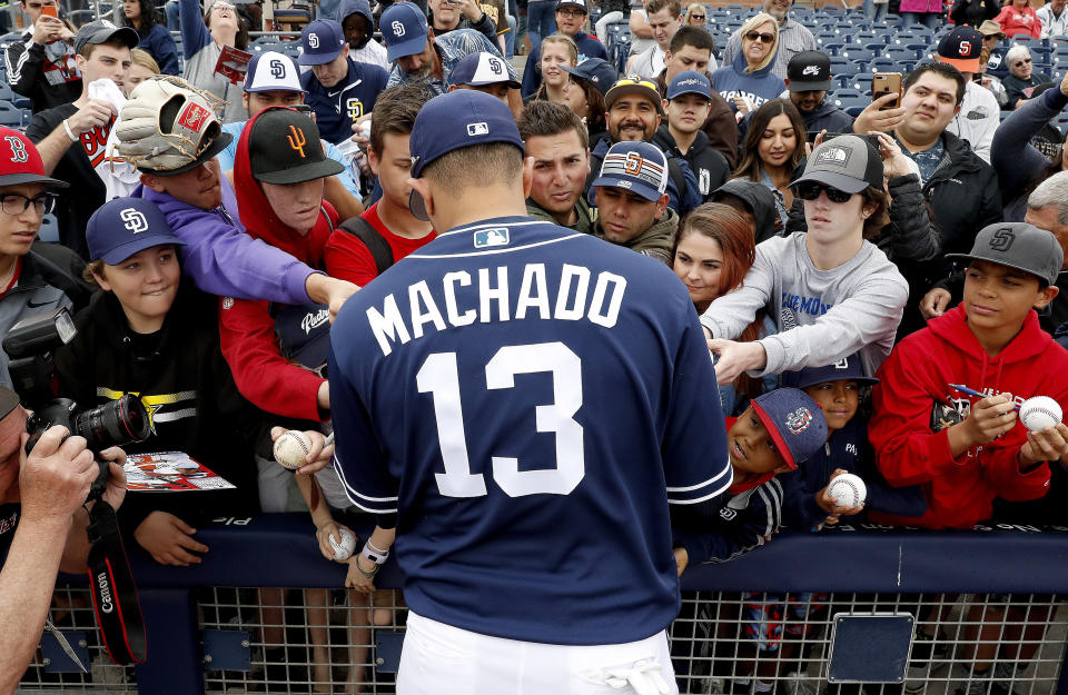 San Diego Padres' Manny Machado (13) signs autographs for fans prior to a spring training baseball game against the San Francisco Giants, Saturday, March 2, 2019, in Peoria, Ariz. (AP Photo/Matt York)