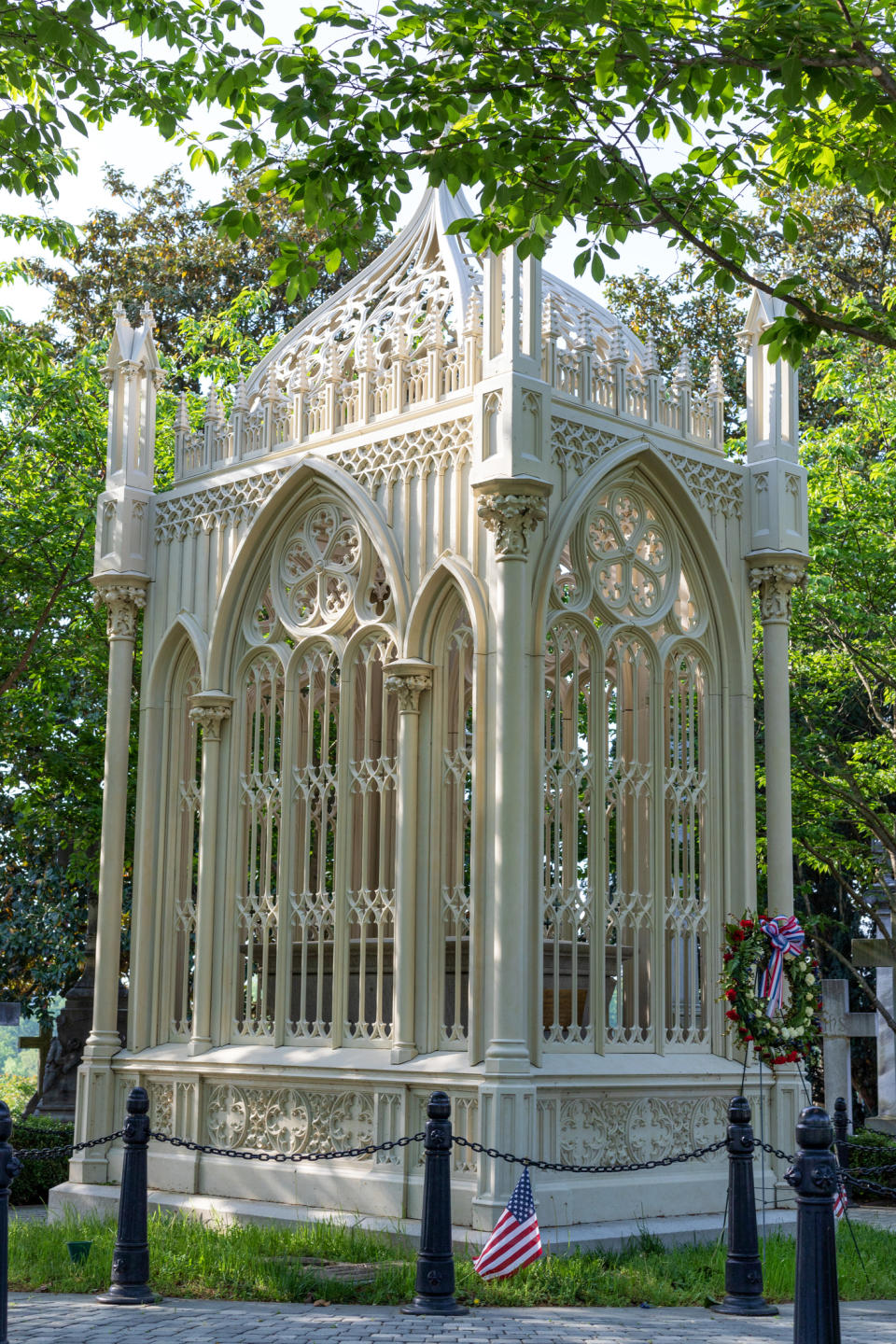 Gothic-style outdoor memorial structure with an American flag and wreath at its base