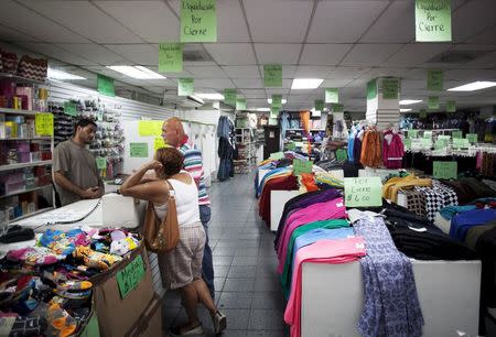 People stand inside a clothing store with signs reading "Closing down sale" in Arecibo, Puerto Rico, June 29, 2015. REUTERS/Alvin Baez-Hernandez