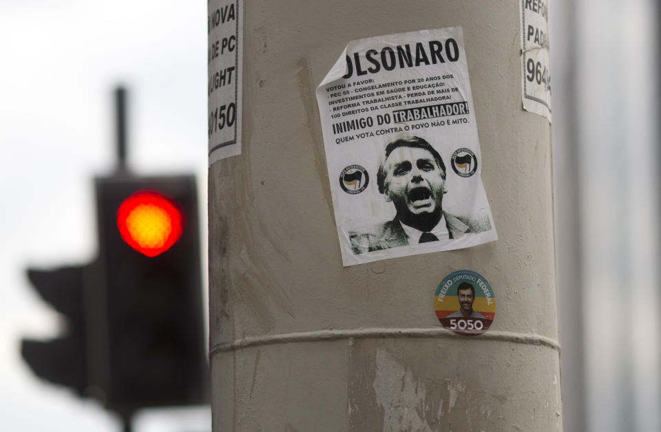 In this Oct. 17, 2018 photo, a sticker calling presidential candidate Jair Bolsonaro as an "Enemy of the worker" covers a street column in Rio de Janeiro, Brazil. Bolsonaro, a former army captain, is reviled by many for his praise for Brazil’s 1964-1985 military dictatorship, and his offensive comments about gays, blacks and women. (AP Photo/Beatrice Christofaro)