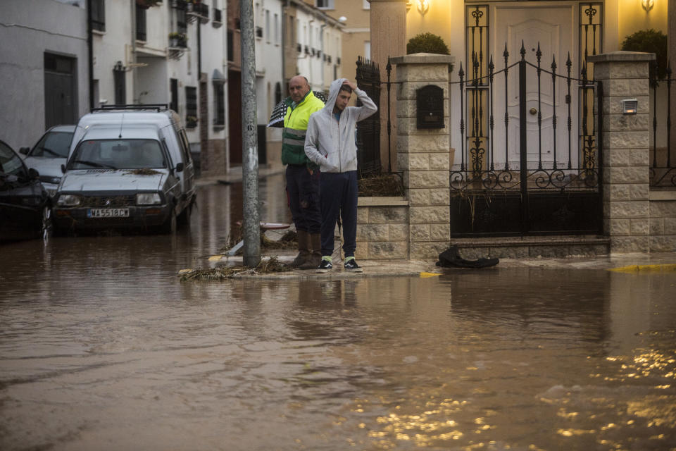 People observe flood water at their doorstep at the village of Campillos, Spain, where heavy rain and floods have caused severe damage and the death of a firefighter according to Spanish authorities Sunday, Oct. 21 2018. Emergency services for the southern region of Andalusia say that the firefighter went missing when his truck overturned on a flooded road during heavy rains that fell through the night, and his body was found after a search Sunday morning. (AP Photo/Javier Fergo)