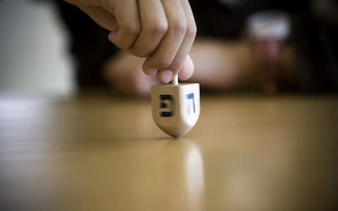 An Israeli boy spins a Dreidel as he takes part in a competition during the Jewish festival of Hanukkah - Credit: JONATHAN NACKSTRAND/AFP