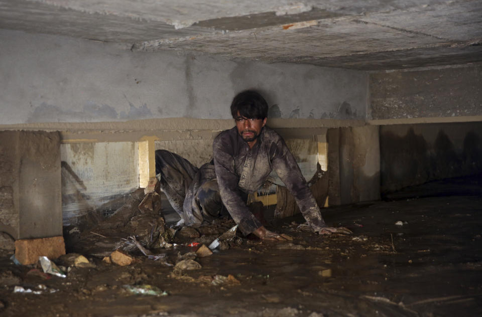 An Afghan man looks for belongings in his house that was damaged by a mudslide, in the Parwan province, north of Kabul, Afghanistan, Thursday, Aug. 27, 2020. The death toll from heavy flooding in northern and eastern Afghanistan rose to at least 150 on Thursday, with scores more injured as rescue crews searched for survivors beneath the mud and rubble of collapsed houses, officials said. (AP Photo/Rahmat Gul)