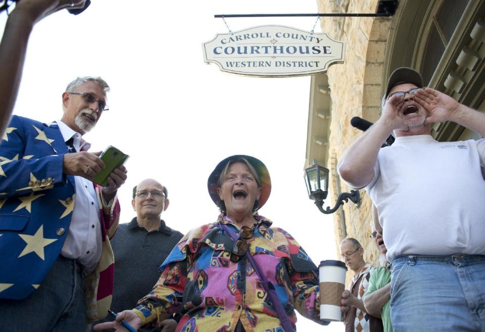 Sheila McFadden, center, and Ken Riley, right, yell words of encouragement at the crowd gathered in front of the Carroll County Courthouse after initially being turned away for a marriage license in Eureka Springs, Ark., Saturday, May 10, 2014, in Eureka Springs, Ark. Same-sex couples were eventually granted marriage licenses, Saturday, in Eureka Springs after a judge overturned Amendment 83, which banned same-sex marriage in the state of Arkansas. (AP Photo/Sarah Bentham)