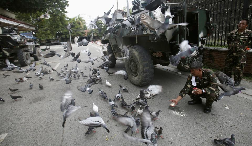 Government soldiers of Task Force Zamboanga (TFZ) feed pigeons near a military command post during a lull in fighting with Muslim rebels of Moro National Liberation Front (MNLF), in Zamboanga city