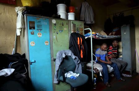 Zakhele Ntsele (L) sits on a bed with a friend in a room he shares with fourteen other men at Jeppestown men's hostel in Johannesburg May 19, 2015. REUTERS/Siphiwe Sibeko