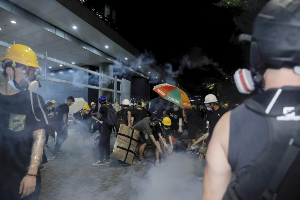 Protesters pour water on tear gas canisters at the Legislative Council in Hong Kong, during the early hours of Tuesday, July 2, 2019. Protesters in Hong Kong took over the legislature's main building Friday night, tearing down portraits of legislative leaders and spray painting pro-democracy slogans on the walls of the main chamber.(AP Photo/Kin Cheung)