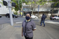 Sonia Guevara poses for a photo, Wednesday, May 18, 2022, outside the Hilton hotel where she works as a housekeeper in downtown Seattle. Many hotels across the United States have done away with daily housekeeping service, making what was already one of the toughest jobs in the hospitality industry even more grueling. (AP Photo/Ted S. Warren)