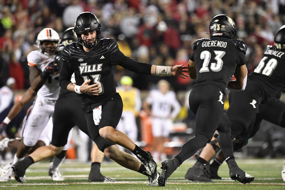 Louisville quarterback Jack Plummer (13) hands off the ball to running back Isaac Guerendo (23) during the second half of an NCAA college football game against Virginia in Louisville, Ky., Thursday, Nov. 9, 2023. (AP Photo/Timothy D. Easley)