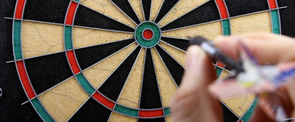 hand throwing dart to dartboard