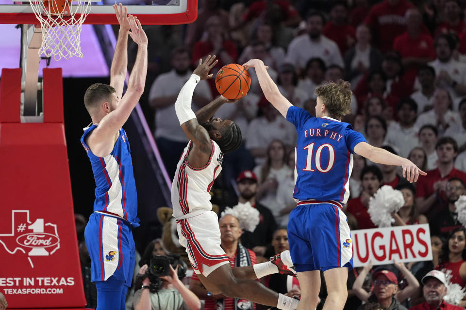 Houston's Jamal Shead (1) goes up for a shot as Kansas' Johnny Furphy (10) and Hunter Dickinson defend during the first half of an NCAA college basketball game Saturday, March 9, 2024, in Houston. (AP Photo/David J. Phillip)