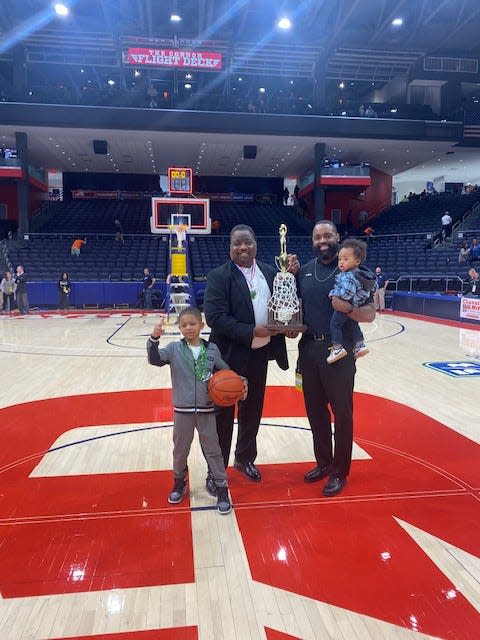 Willie McGee, second from right, smiles while holding his his son, Illya McGee, and standing next to his brother, Illya McGee, and nephew, Angelo McGee in 2022 after the St. Vincent-St. Mary boys basketball team won the Division II state championship at the University of Dayton Arena.