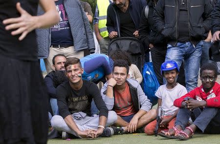 Migrants watch a show presented by a troupe of artists at a makeshift camp outside the foreign office in Brussels, Belgium, September 9, 2015. At least 850,000 people are expected to cross the Mediterranean seeking refuge in Europe this year and next, the United Nations said on Tuesday, giving estimates that already look conservative. REUTERS/Yves Herman - RTSC11