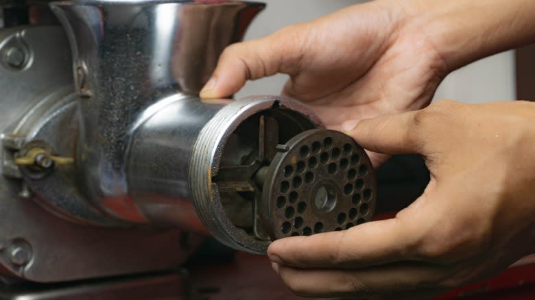 hands attaching grinder plate
