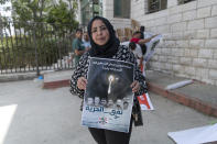 Sahar Abdullah carries a poster with pictures of the six Palestinian prisoners who escaped from an Israeli jail that says "the freedom tunnel," during a protest in the West Bank city of Ramallah, Tuesday, Sept. 14, 2021. The cinematic escape of six prisoners who tunneled out of an Israeli penitentiary shone a light on Israel's mass incarceration of Palestinians, one of the many bitter fruits of the conflict. (AP Photo/Nasser Nasser)