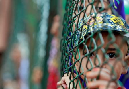 Kashmiri child looks from behind a fence at a protest site in Srinagar