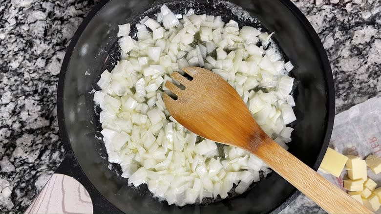 onions sauteeing in pan with wooden spoon