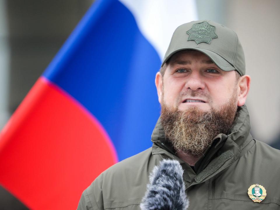 Chechen leader Ramzan Kadyrov at a microphone in front of a Russian flag.