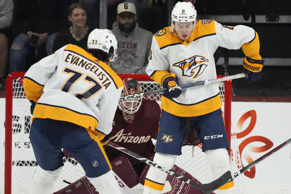 Nashville Predators center Cody Glass (8) tries to redirect the puck in front of Arizona Coyotes goaltender Connor Ingram, center, as Predators right wing Luke Evangelista (77) looks on during the first period of an NHL hockey game Saturday, Jan. 20, 2024, in Tempe, Ariz. (AP Photo/Ross D. Franklin)