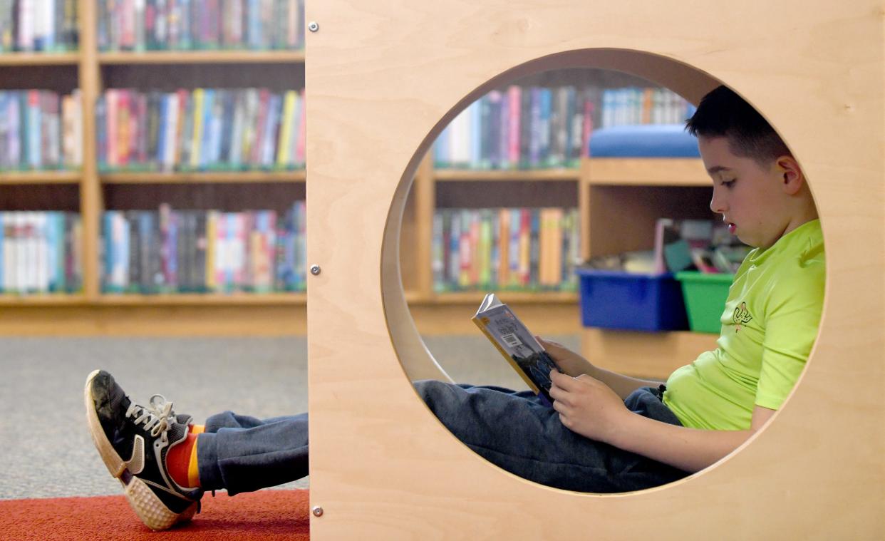 Logan Shankle, 10, of Perry Township takes cover while reading Monday, April 1, 2024, at Massillon Public Library on a rainy day off from school.