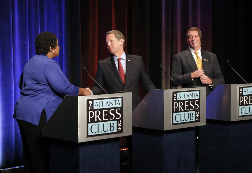 Democratic candidate for Georgia Governor Stacey Abrams, left, and Republican Brian Kemp greet each other as Libertarian Ted Metz, right, looks on before a debate Tuesday, Oct. 23, 2018, in Atlanta. (AP Photo/John Bazemore, Pool)