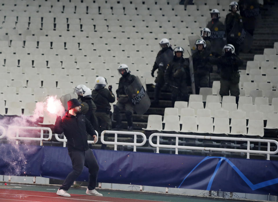 A fan throws a flare towards Ajax supporters during a Group E Champions League soccer match between AEK Athens and Ajax at the Olympic Stadium in Athens, Tuesday, Nov. 27, 2018. (AP Photo/Thanassis Stavrakis)