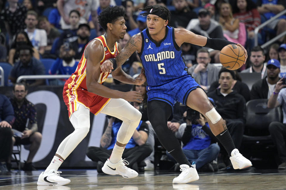 Orlando Magic forward Paolo Banchero (5) is defended by Atlanta Hawks forward De'Andre Hunter (12) during the first half of an NBA basketball game Wednesday, Nov. 30, 2022, in Orlando, Fla. (AP Photo/Phelan M. Ebenhack)