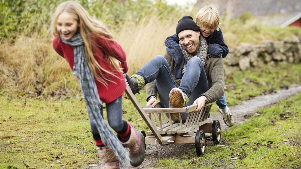 Un padre jugando con sus dos hijos en un campo