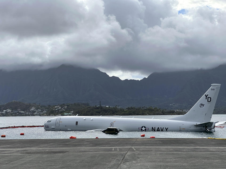 FILE - A Navy P-8A plane that overshot a runway at Marine Corps Base Hawaii and landed in shallow water offshore sits on a reef and sand in Kaneohe Bay, Hawaii, on Nov. 27, 2023. The U.S. Navy says underwater footage shows two points where the large plane is touching coral in a Hawaii bay. (AP Photo/Audrey McAvoy,File)