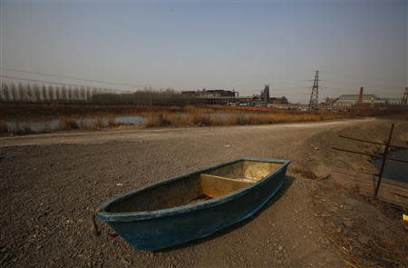 A boat is seen on the ground next to a fish farm located near an abandoned steel mill of Qingquan Steel Group in Qianying township, Hebei province February 18, 2014. REUTERS/Petar Kujundzic