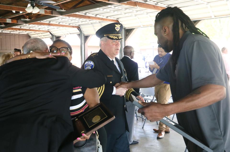 Mayor Dan Horrigan hugs Lisa Stewart, the wife of the late officer Edward Stewart, as Akron Police Chief Steve Mylett shakes the hand of Jason Stewart at the Akron police memorial service Wednesday.