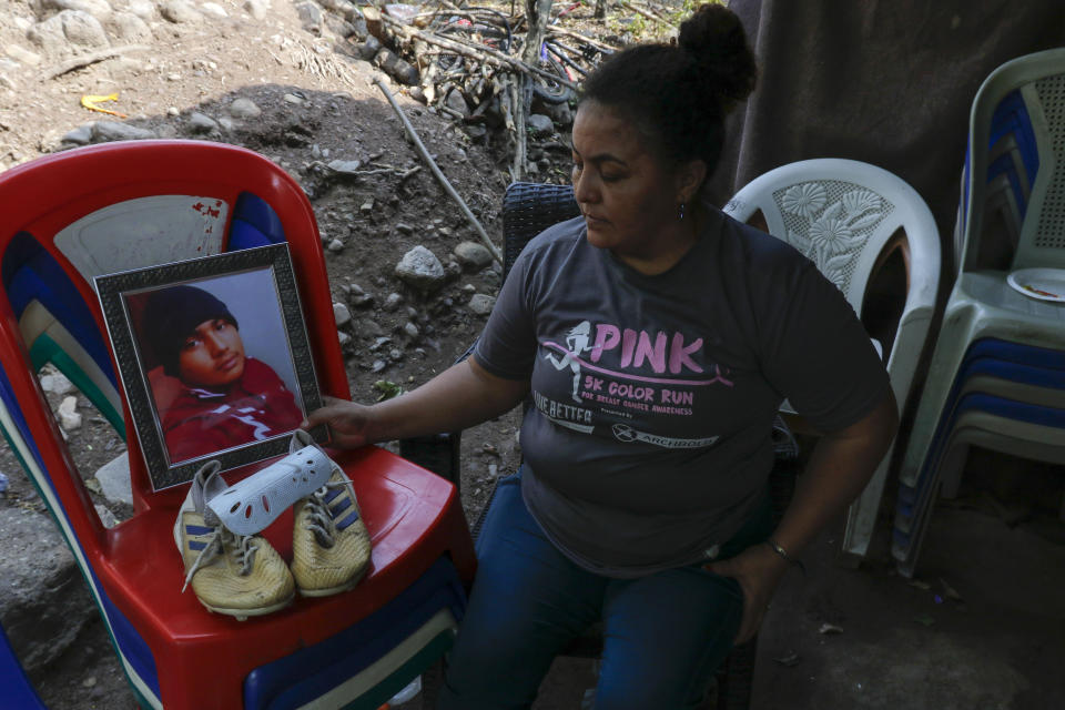 Norma Espinoza sits next to a portrait of her son Angel Maradiaga, at her home in Olanchito, Honduras, Saturday, May 13, 2023. Maradiaga, 17, who was detained at a facility in Safety Harbor, Florida, died Wednesday. Epinoza is demanding answers from American officials, saying her son had no known illnesses and had not shown any signs of being sick before his death. (AP Photo/Delmer Martinez)