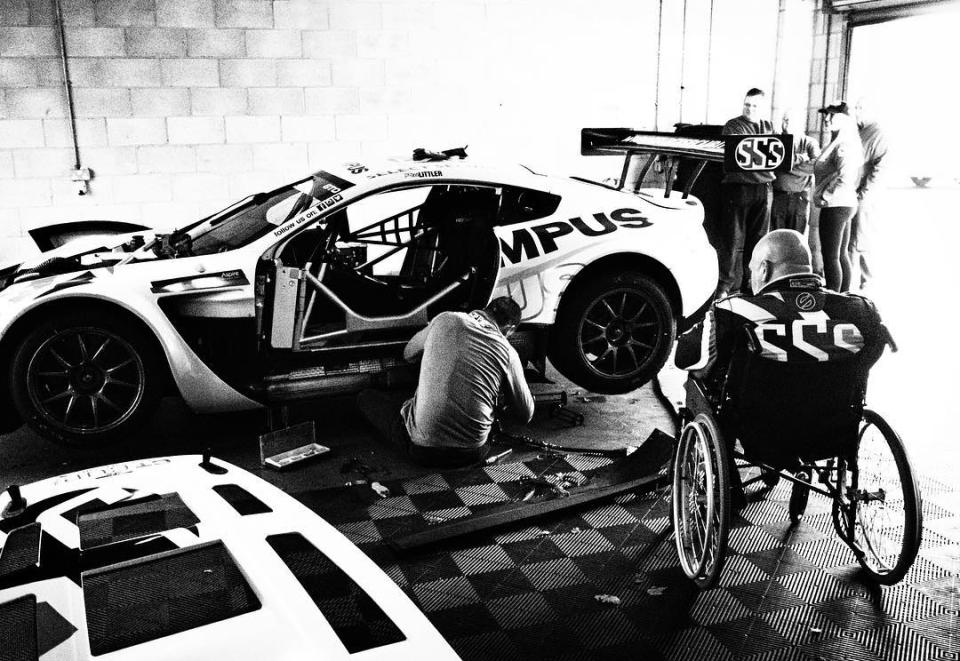 Olympus 9mm body cap image of an Aston Martin Olympus race car, with driver in a wheelchair