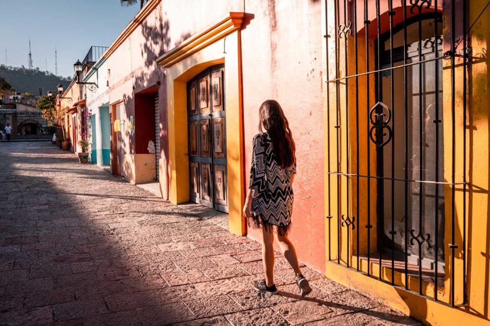 A young woman walking past colorful facades in Oaxaca, Mexico