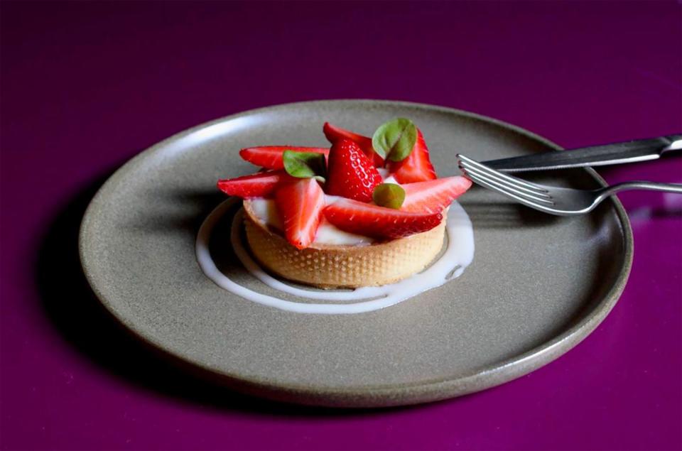 tart with strawberries on a gray plate against a purple background