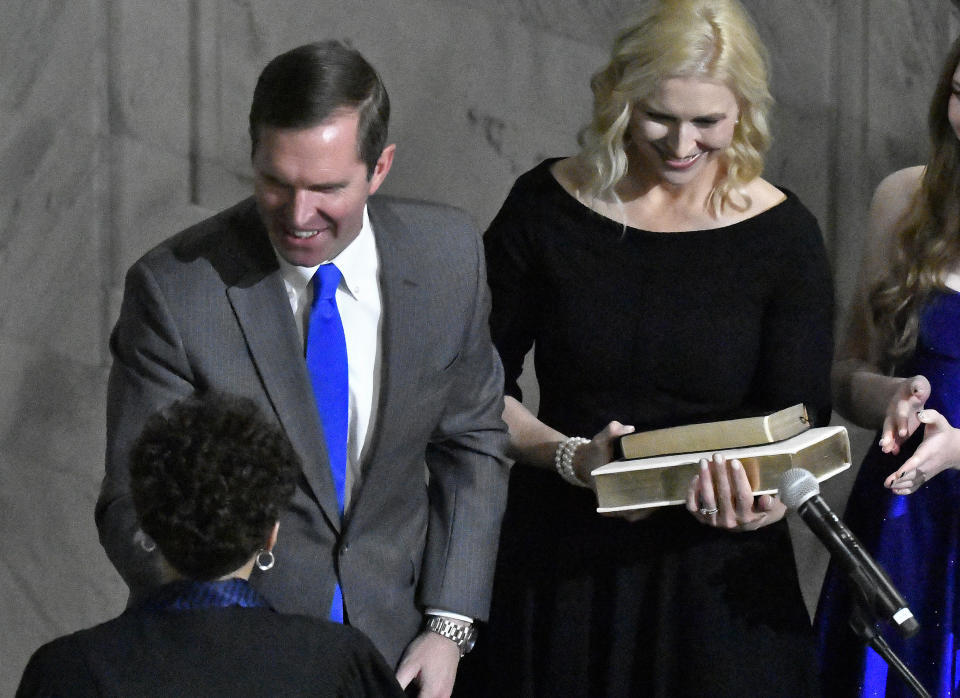 Kentucky Gov. Andy Beshear shakes hands with Judge Pamela Goodwine after taking the oath of office in the Capitol Rotunda in Frankfort, Ky., early Tuesday, Dec. 12, 2023. Next to Beshear is his wife, Britainy Beshear. (AP Photo/Timothy D. Easley)