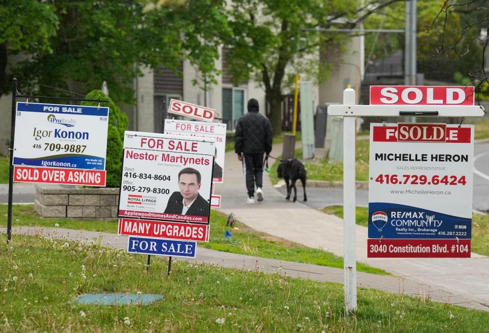 A person walks past multiple for-sale and sold real estate signs in Mississauga, Ont., on Wednesday, May 24, 2023. 