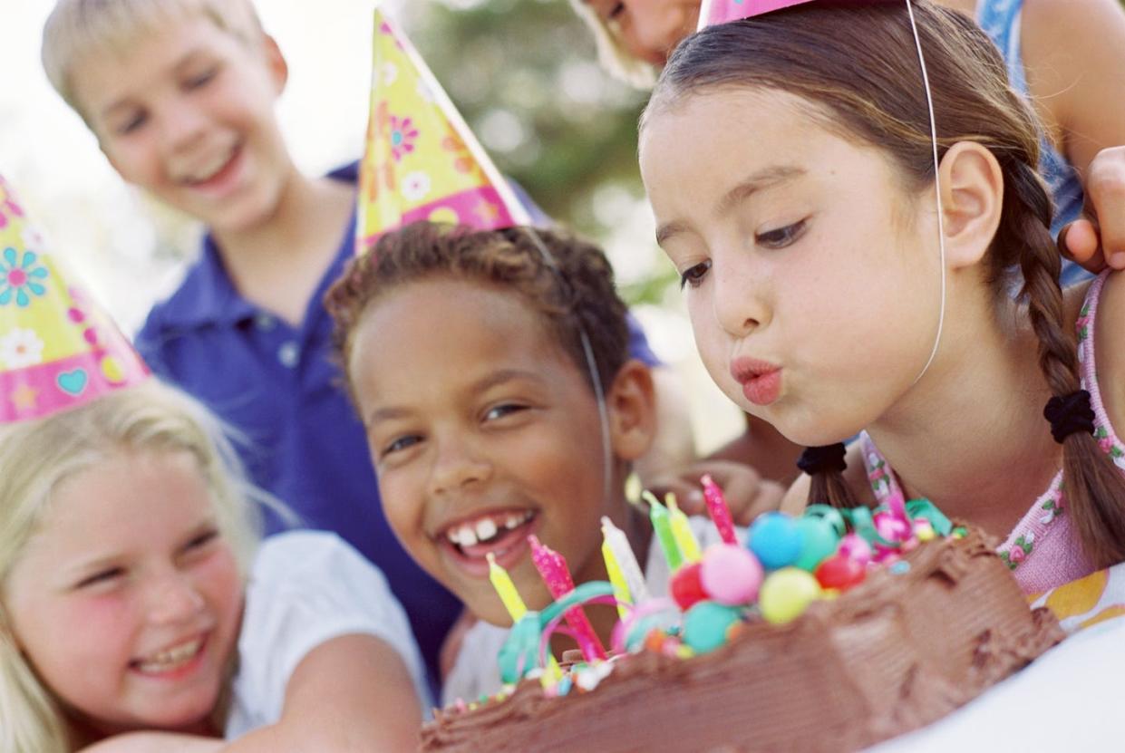 group of children blowing out candles on chocolate cake