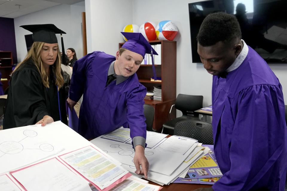 Apr 28, 2023; Phoenix, Ariz., U.S.; LOPES Academy program manager Allison Kolanko (left) helps Kyle Bragelman and Jaden Lowery gather up some of their class projects. LOPES Academy is a nondegree program for individuals with intellectual and developmental disabilities at Grand Canyon University.