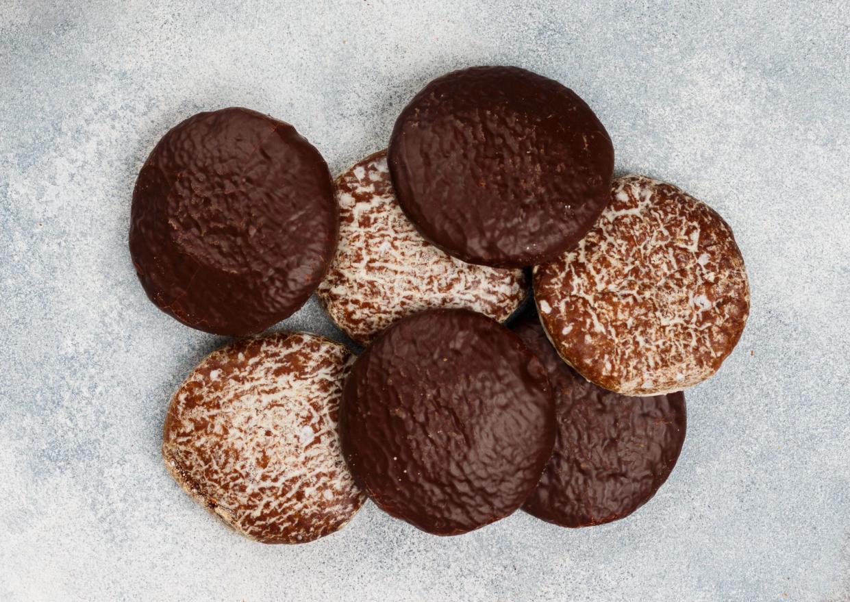 Nuremberg gingerbreads with nuts (almonds, hazelnuts, walnuts) in chocolate and sugar glaze. Lebkuchen. Traditional Christmas and new year treats. Selective focus, top view